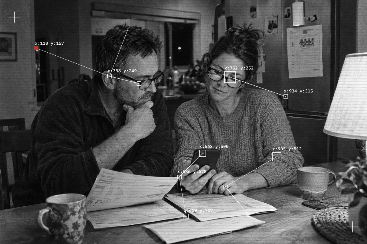 A couple in their forties reading a mortgage statement and a phone at their dining table at night