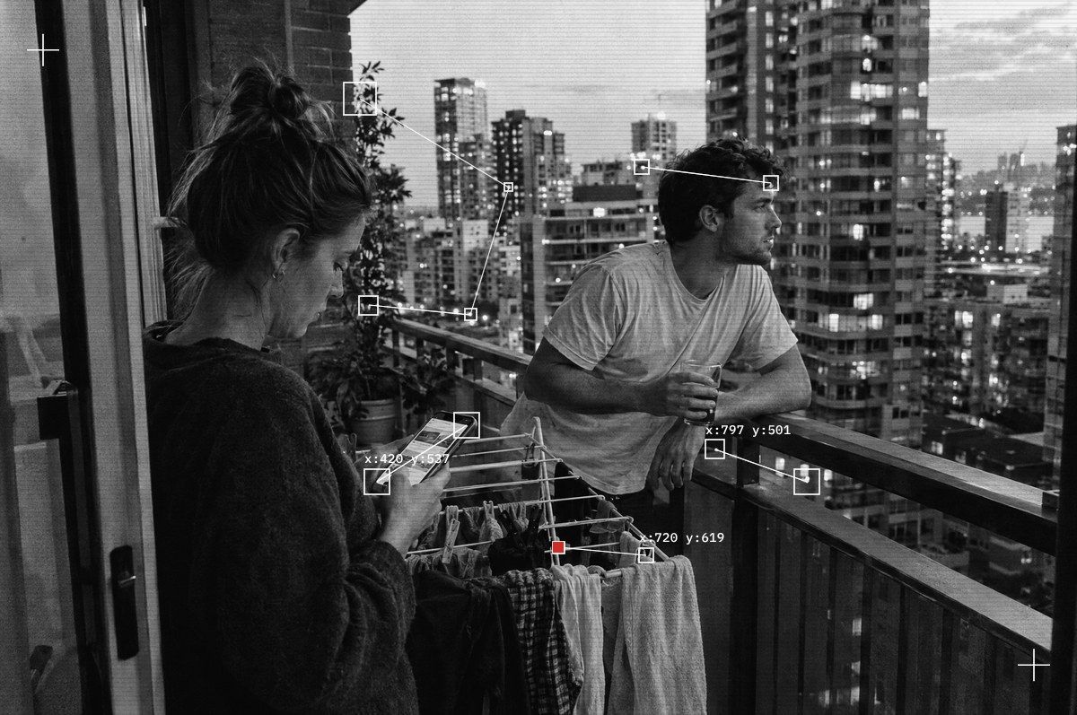 A young couple on their rented apartment balcony at dusk, city skyline in the distance
