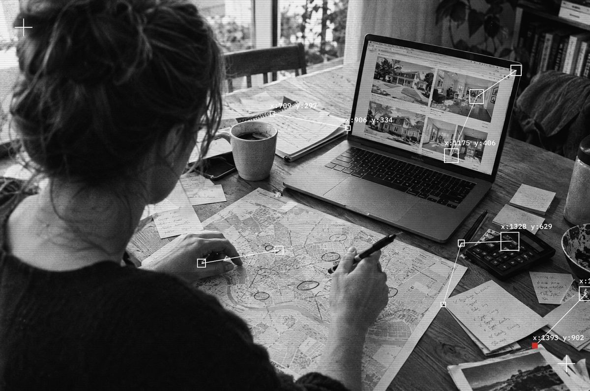 Someone marking up a printed street map beside a laptop full of listings