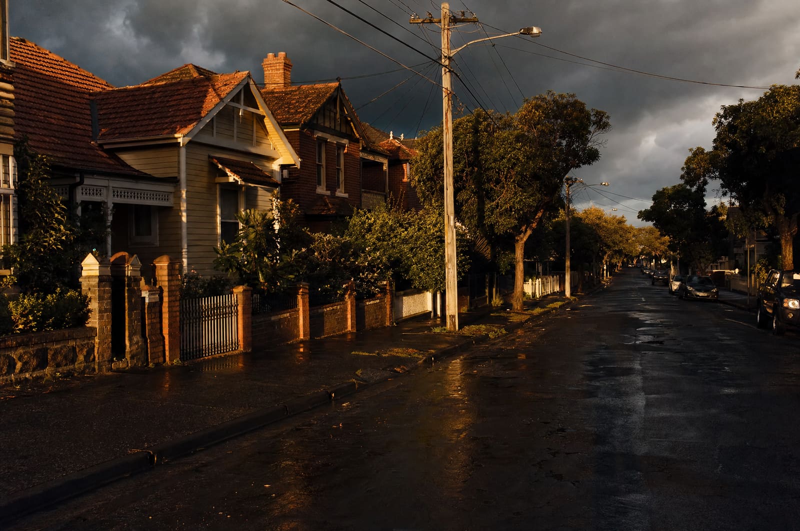 Warm sunlight breaking through storm clouds over an established Australian suburban street